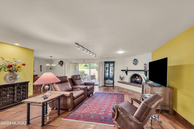 tiled living room featuring a brick fireplace, track lighting, and an inviting chandelier