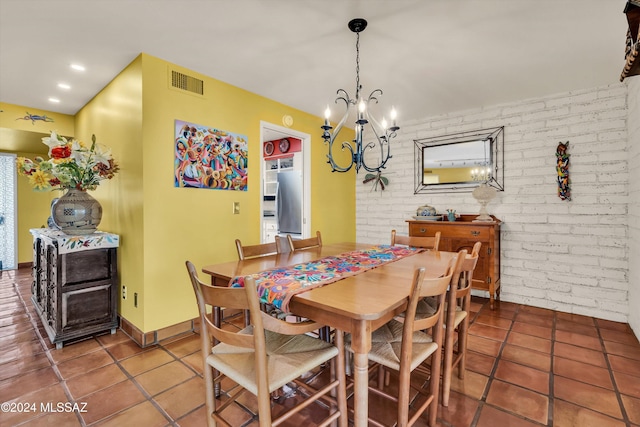 tiled dining space with an inviting chandelier and brick wall