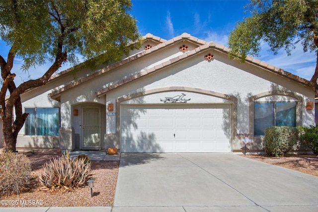 mediterranean / spanish-style home with a tile roof, an attached garage, driveway, and stucco siding