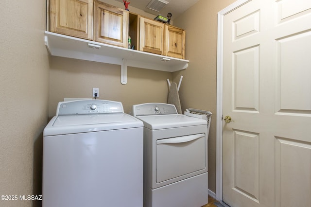 washroom with visible vents, cabinet space, and separate washer and dryer