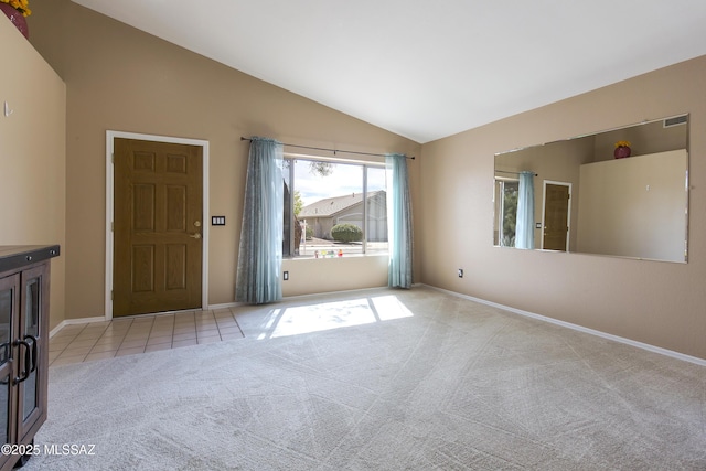 carpeted empty room featuring tile patterned flooring, visible vents, baseboards, and lofted ceiling