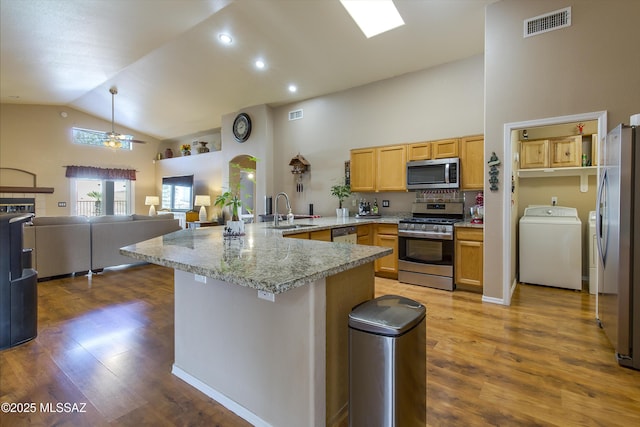 kitchen with visible vents, a peninsula, a sink, stainless steel appliances, and open floor plan