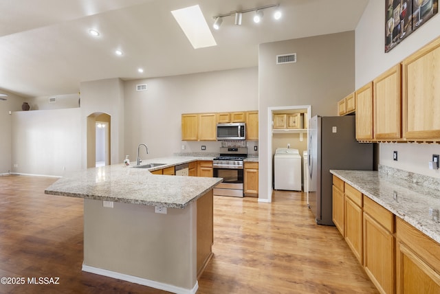 10187 E Watson Dr, Tucson, AZ 85730 - kitchen featuring washer / dryer, stainless steel appliances, a sink, a peninsula, and arched walkways