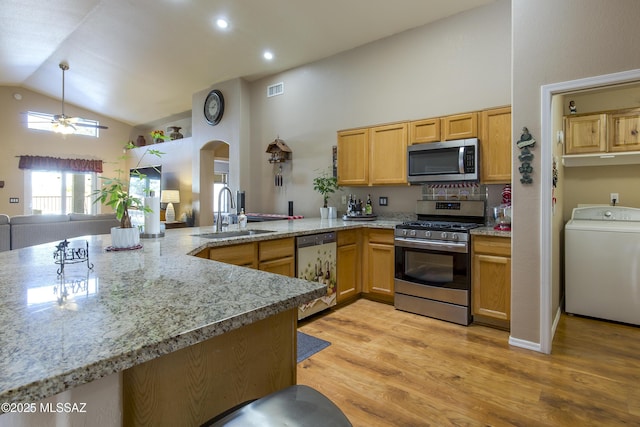 kitchen featuring a sink, open floor plan, stainless steel appliances, arched walkways, and washer / dryer