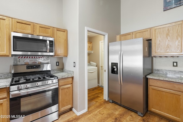 10187 E Watson Dr, Tucson, AZ 85730 - kitchen featuring appliances with stainless steel finishes, light wood finished floors, light stone counters, light brown cabinetry, and a high ceiling