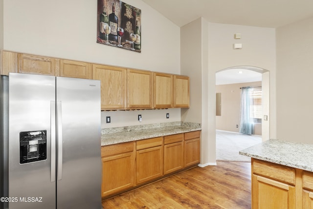 10187 E Watson Dr, Tucson, AZ 85730 - kitchen with stainless steel fridge, arched walkways, light wood-style floors, and light stone countertops