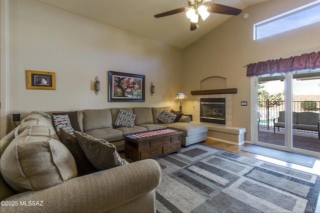 living area featuring wood finished floors, high vaulted ceiling, a fireplace, and a ceiling fan