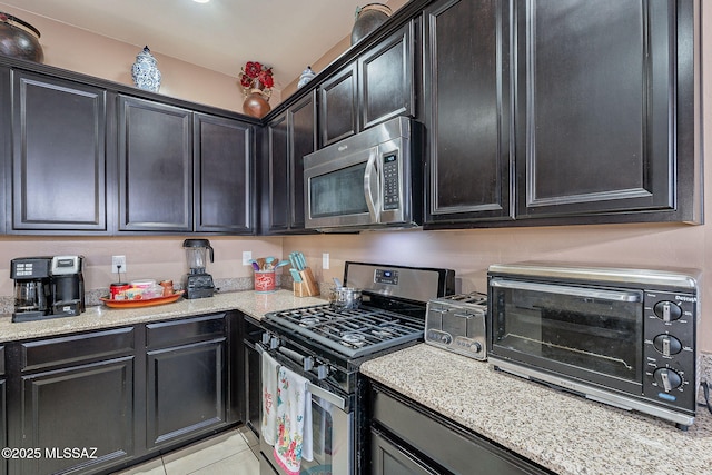 kitchen featuring light stone countertops, light tile patterned floors, and appliances with stainless steel finishes