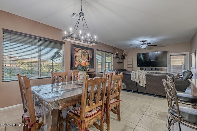 tiled dining room featuring ceiling fan with notable chandelier and a healthy amount of sunlight