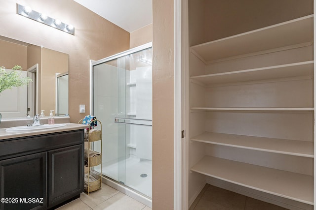 bathroom with tile patterned floors, vanity, and a shower with door