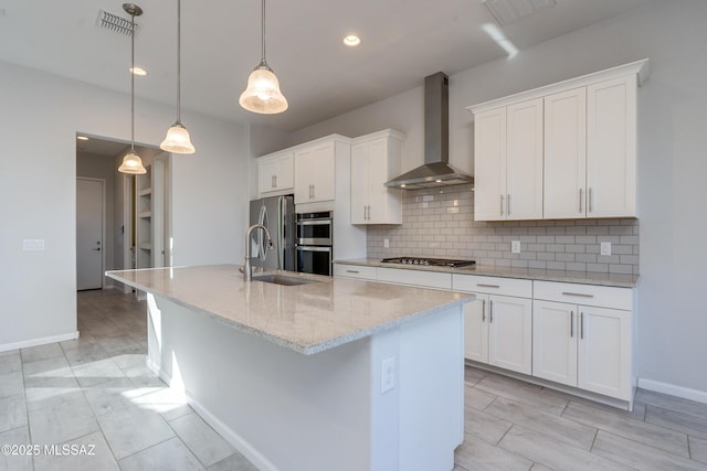 kitchen with white cabinetry, sink, wall chimney exhaust hood, and decorative light fixtures