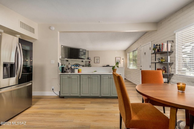 kitchen with brick wall, light wood-type flooring, stainless steel fridge with ice dispenser, and beam ceiling