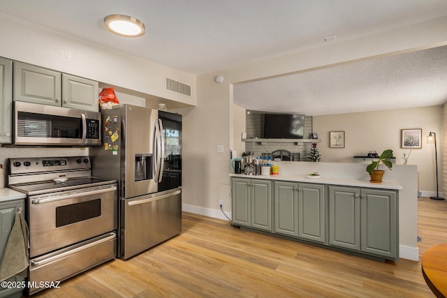 kitchen with appliances with stainless steel finishes, light hardwood / wood-style flooring, and kitchen peninsula