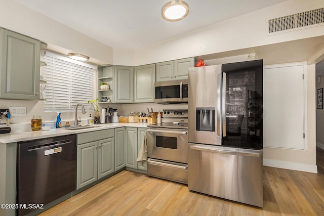 kitchen with sink, stainless steel appliances, and light hardwood / wood-style floors