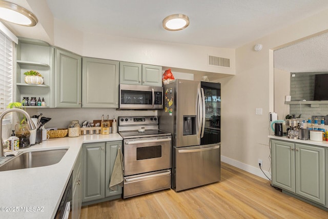 kitchen with stainless steel appliances, sink, and light hardwood / wood-style flooring