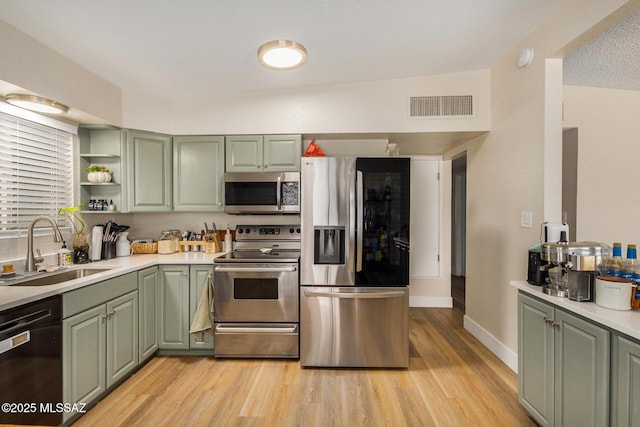 kitchen with sink, stainless steel appliances, light hardwood / wood-style flooring, and green cabinets