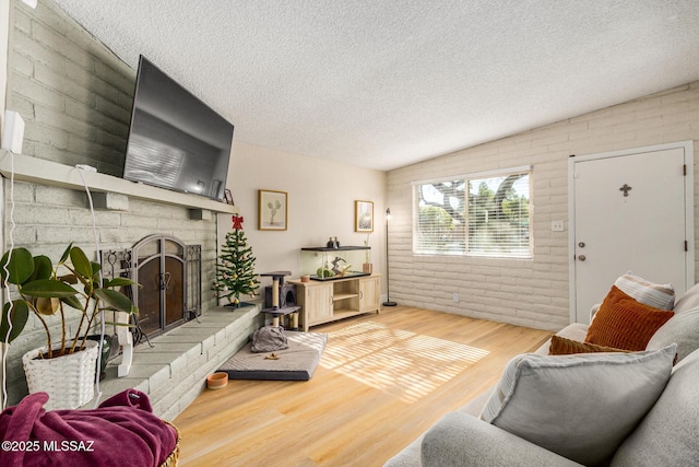 living room with brick wall, a textured ceiling, a fireplace, and wood-type flooring