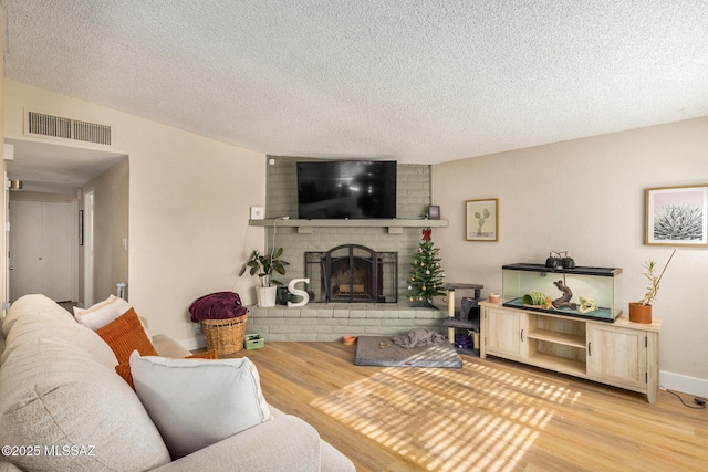 living room featuring a fireplace, a textured ceiling, and light hardwood / wood-style floors