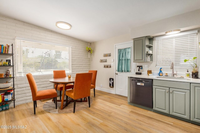 kitchen featuring brick wall, dishwasher, light hardwood / wood-style flooring, and sink