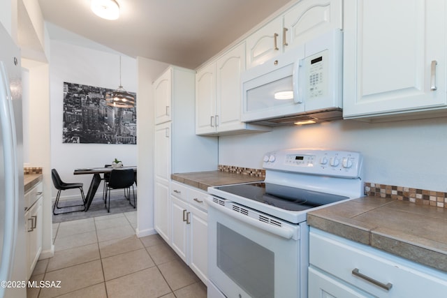 kitchen featuring white cabinets, light tile patterned flooring, and white appliances