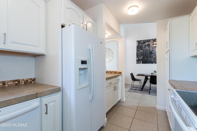 kitchen with light tile patterned floors, white appliances, and white cabinetry