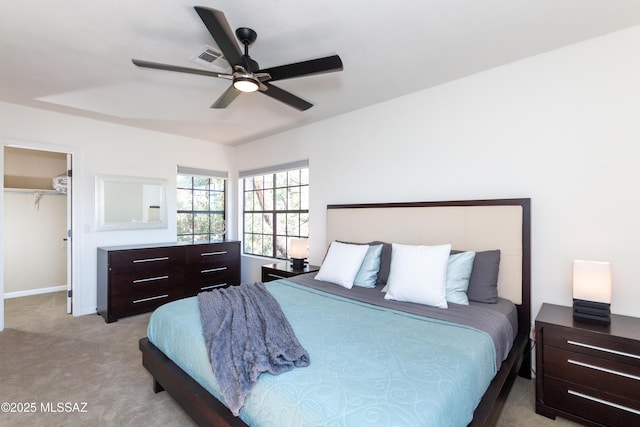 carpeted bedroom featuring a spacious closet, a closet, and ceiling fan