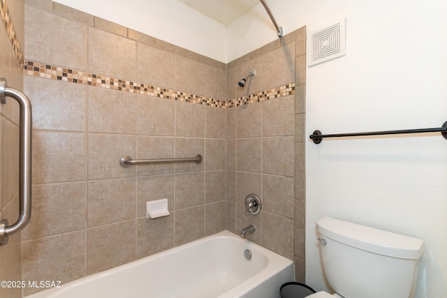 bathroom featuring tiled shower / bath combo and toilet