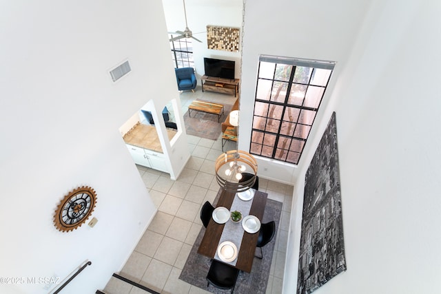 living room with ceiling fan, light tile patterned floors, and a high ceiling