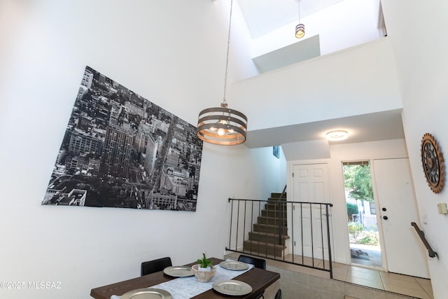 tiled dining area featuring a high ceiling and an inviting chandelier