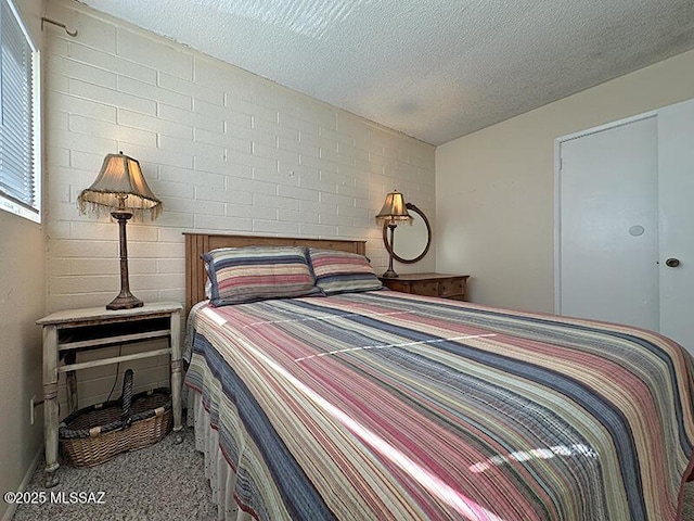 carpeted bedroom featuring brick wall and a textured ceiling