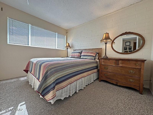 carpeted bedroom with a textured ceiling and brick wall