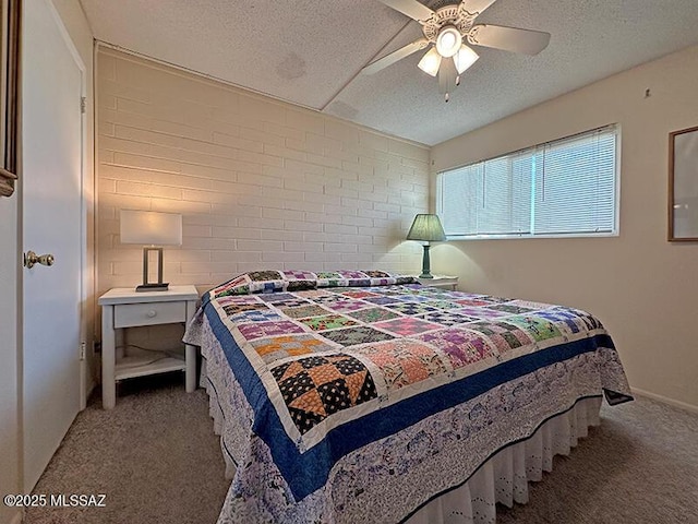 carpeted bedroom with a textured ceiling, ceiling fan, and brick wall