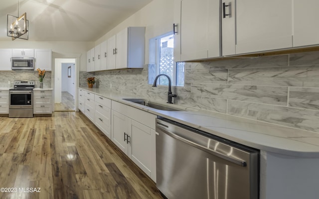 kitchen featuring appliances with stainless steel finishes, tasteful backsplash, sink, pendant lighting, and white cabinets