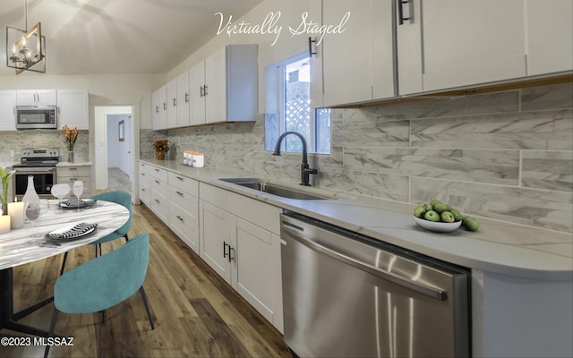 kitchen featuring white cabinetry, sink, hanging light fixtures, backsplash, and appliances with stainless steel finishes