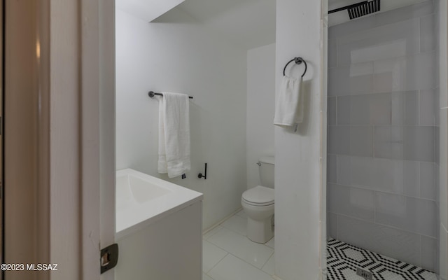 bathroom with tiled shower, tile patterned flooring, vanity, and toilet