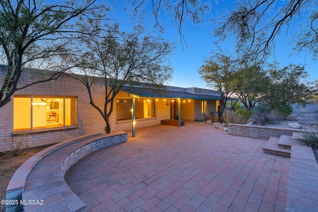 back house at dusk with a patio area