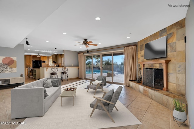 living room featuring ceiling fan, light tile patterned floors, and a tiled fireplace