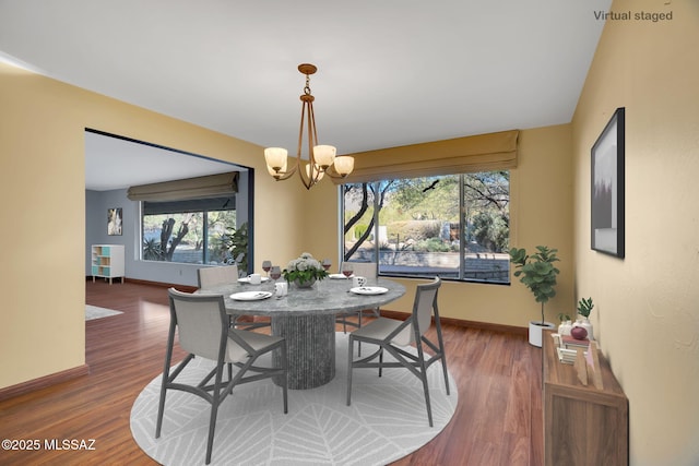 dining room with dark hardwood / wood-style floors and an inviting chandelier