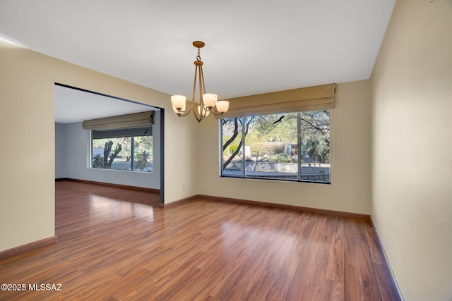 unfurnished room with a chandelier and hardwood / wood-style flooring