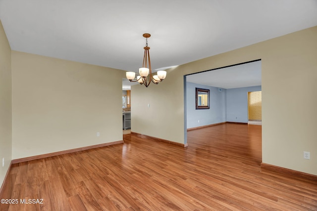 empty room with light hardwood / wood-style floors and a notable chandelier