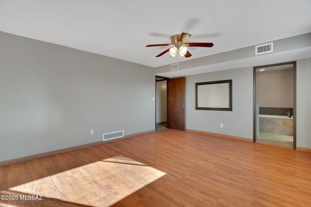 unfurnished bedroom with ceiling fan, ensuite bathroom, and hardwood / wood-style flooring