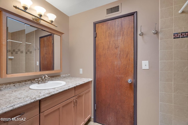 bathroom with tiled shower and vanity