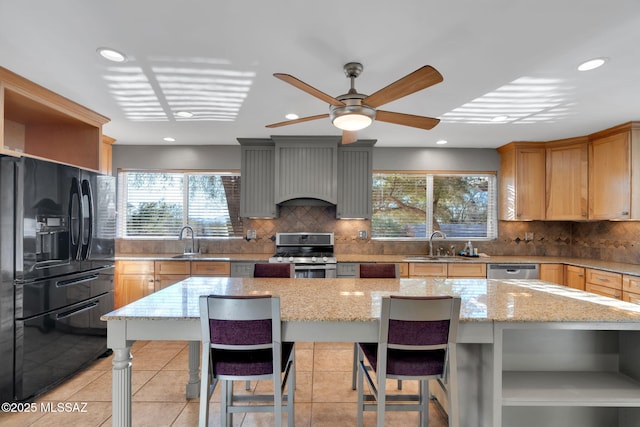 kitchen featuring a breakfast bar area, appliances with stainless steel finishes, a kitchen island, and light stone countertops