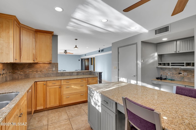 kitchen with ceiling fan, light tile patterned flooring, backsplash, and light stone countertops