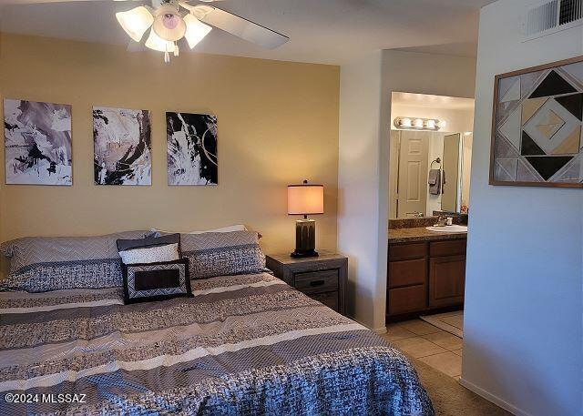 tiled bedroom featuring ceiling fan, sink, and ensuite bath