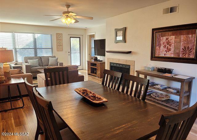 dining area with a fireplace, hardwood / wood-style flooring, and ceiling fan