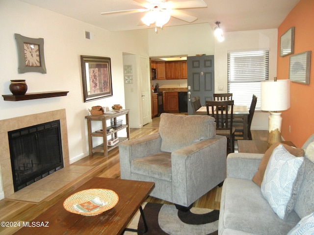 living room with ceiling fan, a fireplace, and light hardwood / wood-style floors