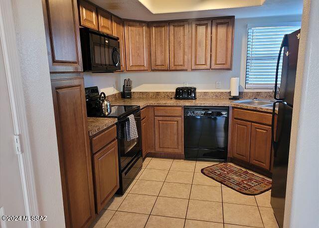 kitchen with black appliances, light tile patterned flooring, and sink