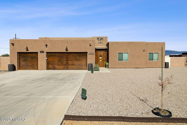 pueblo revival-style home featuring central air condition unit and a garage