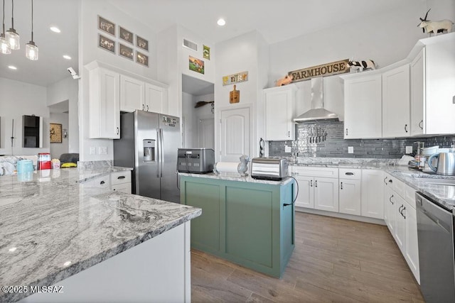 kitchen featuring white cabinets, appliances with stainless steel finishes, and wall chimney exhaust hood